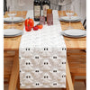 A white table runner with a ghost pattern is set on a wooden table for an autumn or Halloween meal.