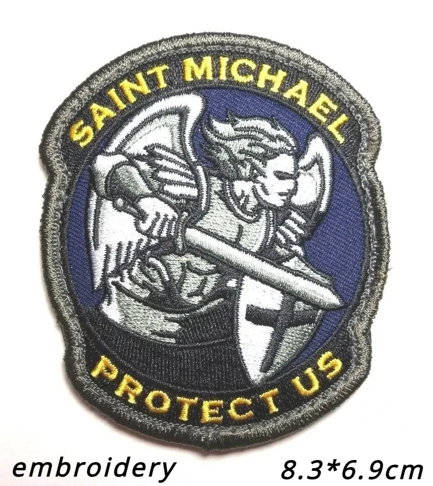 A dark blue embroidered patch featuring a silver archangel St. Michael with wings and a sword, surrounded by yellow text that