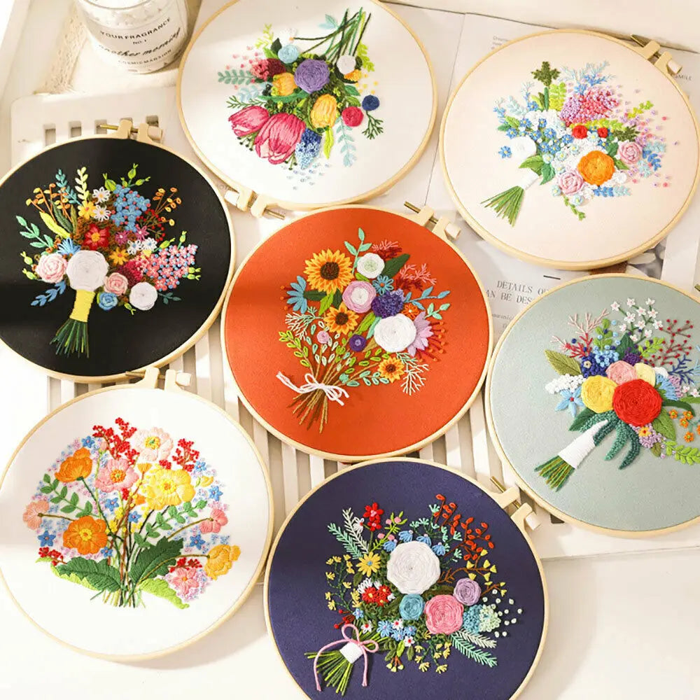 A collection of round embroidery hoops featuring colorful floral cross stitch designs on white, orange, and dark blue backgro