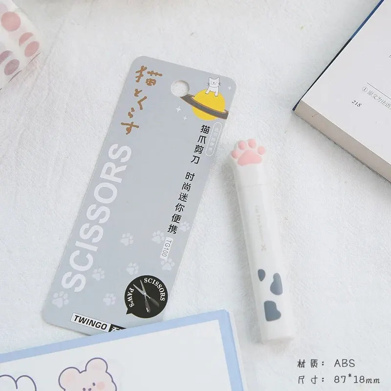 A package of stainless steel cat paw portable scissors with a yellow cat silhouette and branding is shown on a white backgrou