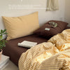 A set of mustard yellow and beige striped bedding, including a pillow and duvet cover, displayed on a bed.