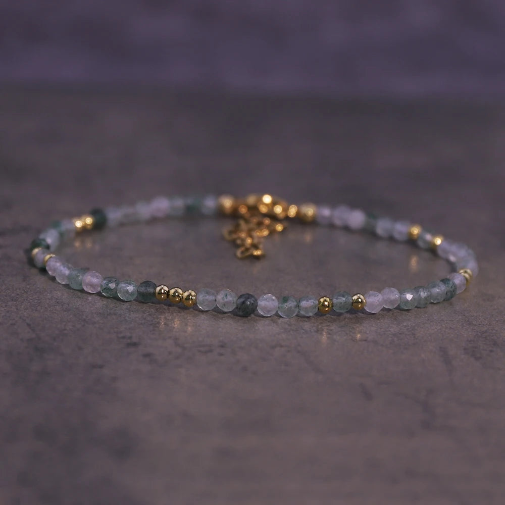 A natural crystal beaded bracelet featuring light green and clear stones with gold accents.