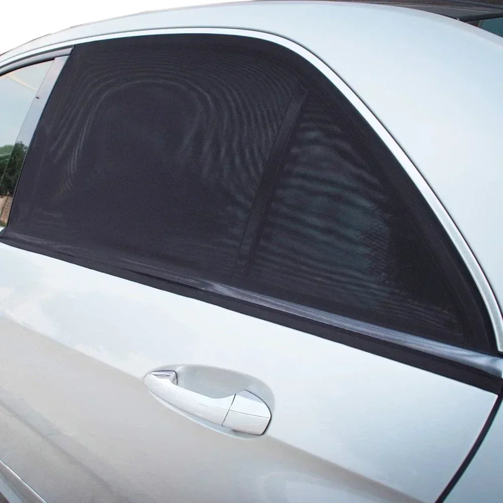A close-up view of a black mosquito mesh sunshade installed on the side window of a silver car.