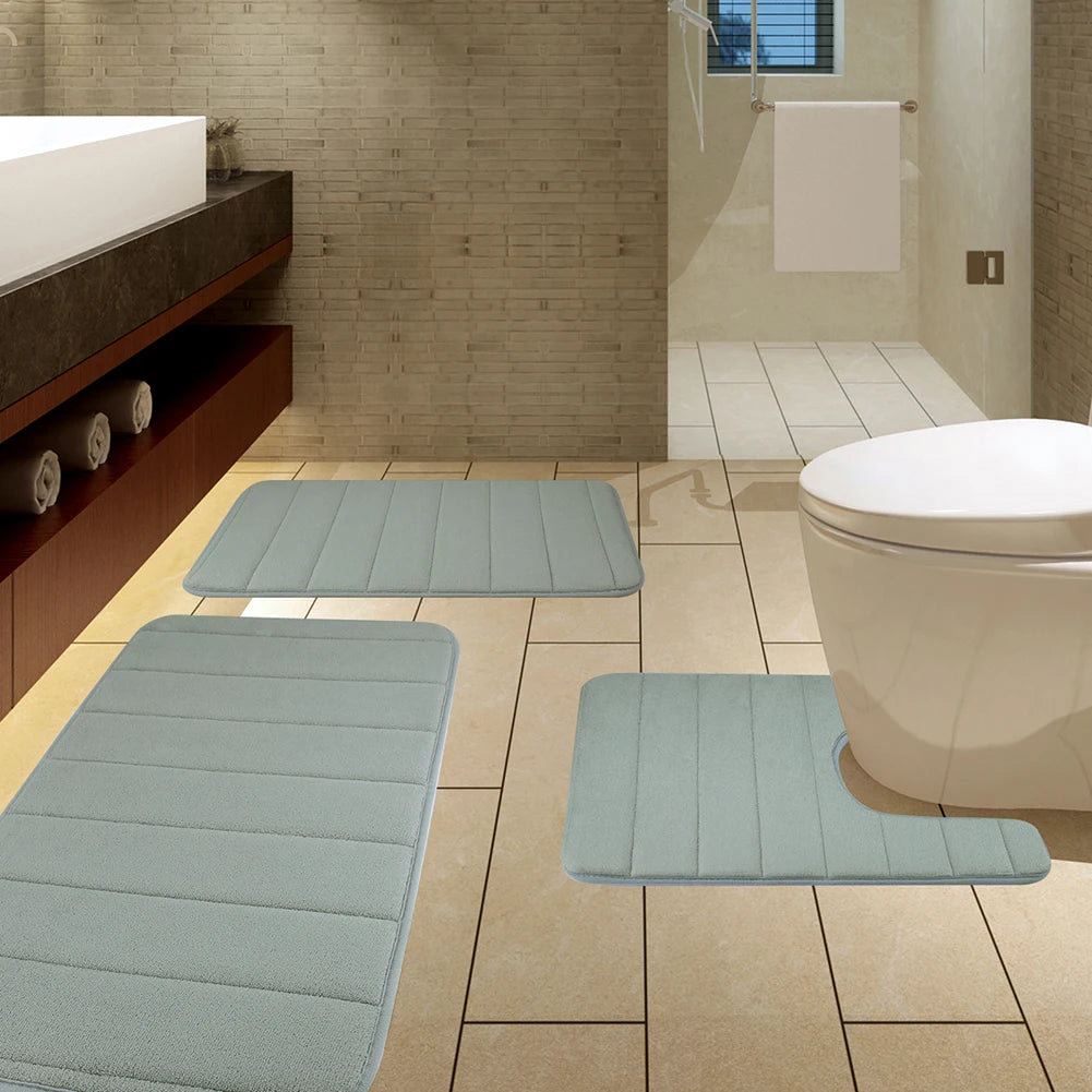 A set of light blue plush memory foam bath mats with non-slip backing placed on a tiled bathroom floor.