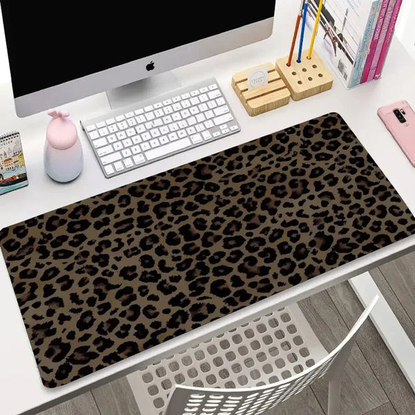 A dark brown leopard print mouse pad with a non-slip rubber base is displayed on a white desk next to a computer monitor and 