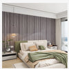 A bedroom featuring a bed with light green bedding and a textured wood grain wallpaper accent wall.