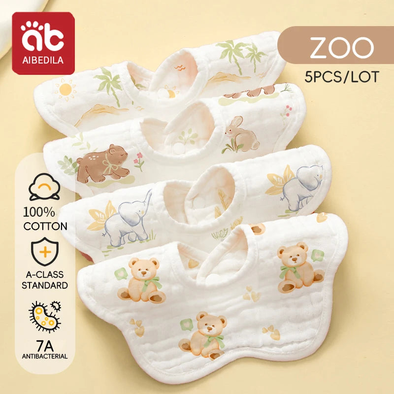 A set of five white cotton muslin bandana bibs with animal designs for babies