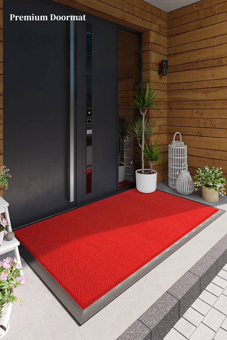 A red premium doormat placed on a gray tiled floor in front of a dark door.