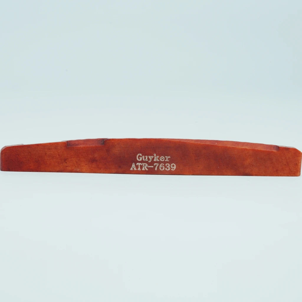 A wooden acoustic guitar bridge saddle with the name Guyker and model number ATR-7639 engraved on it.