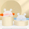 A pair of soft silicone bunny-shaped baby teethers in pink and blue are displayed on a white stand.