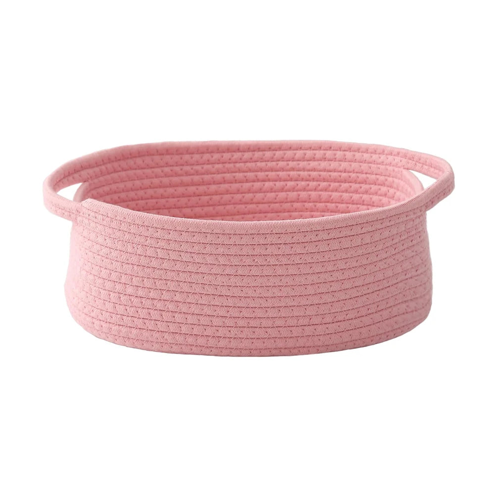 A pink handwoven rope storage basket with handles.