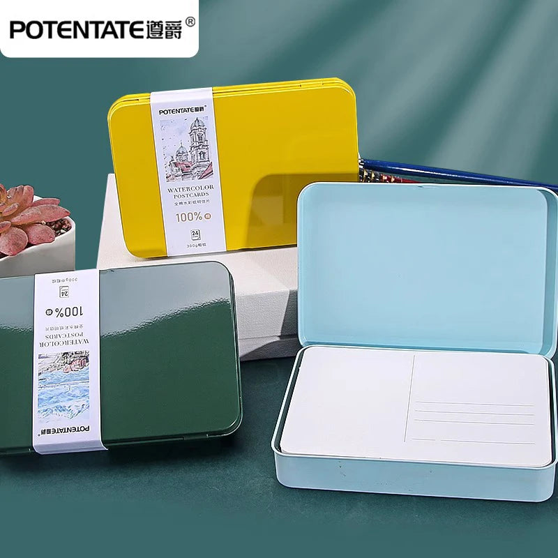 A set of three watercolor paper blocks in yellow, green, and light blue are displayed in their respective tin boxes.
