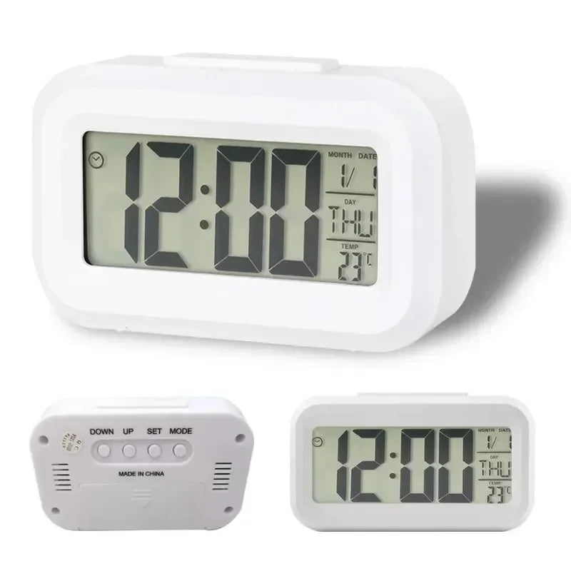 A white compact LED digital alarm clock with a display showing 12:00, featuring separate buttons for set mode and day/date.