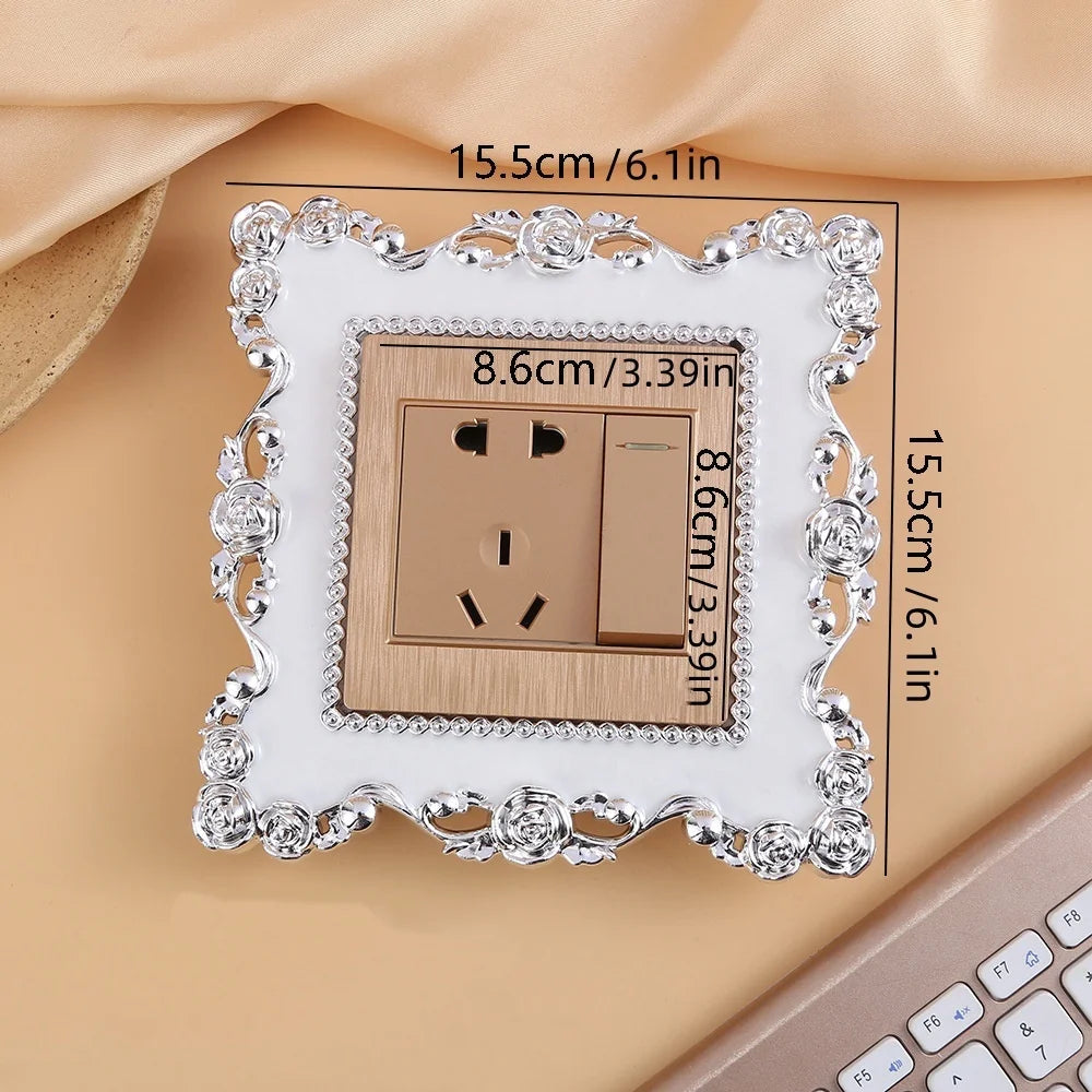 A rectangular switch cover frame with a rose pattern border and a brown electrical outlet inside.