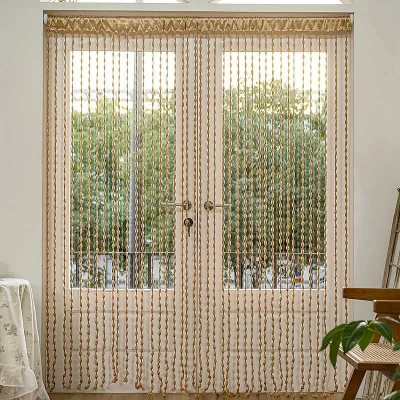 Bohemian tassel curtain with lanterns covering a glass door or window.