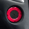 A close-up of a round red button cover with START/STOP markings set into a black car interior panel.