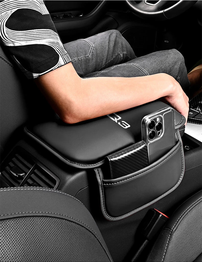 A hand rests on a black car armrest box mat with a storage pocket for an Audi vehicle interior.