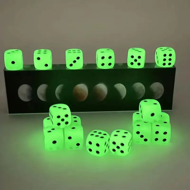 A row of glow-in-the-dark acrylic dice resting on a black surface, with several individual dice scattered in front.
