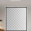 A close-up of a textured, quilted thermal insulated door curtain with a diamond pattern installed in a white frame.