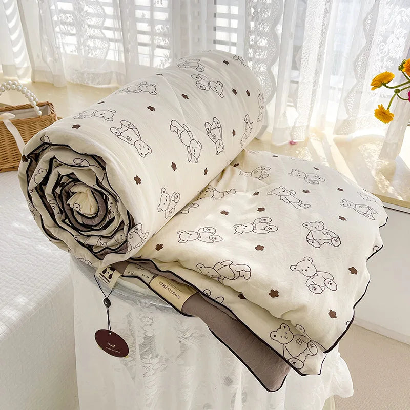 A rolled lightweight washed cotton summer quilt with a floral pattern displayed on a white table.