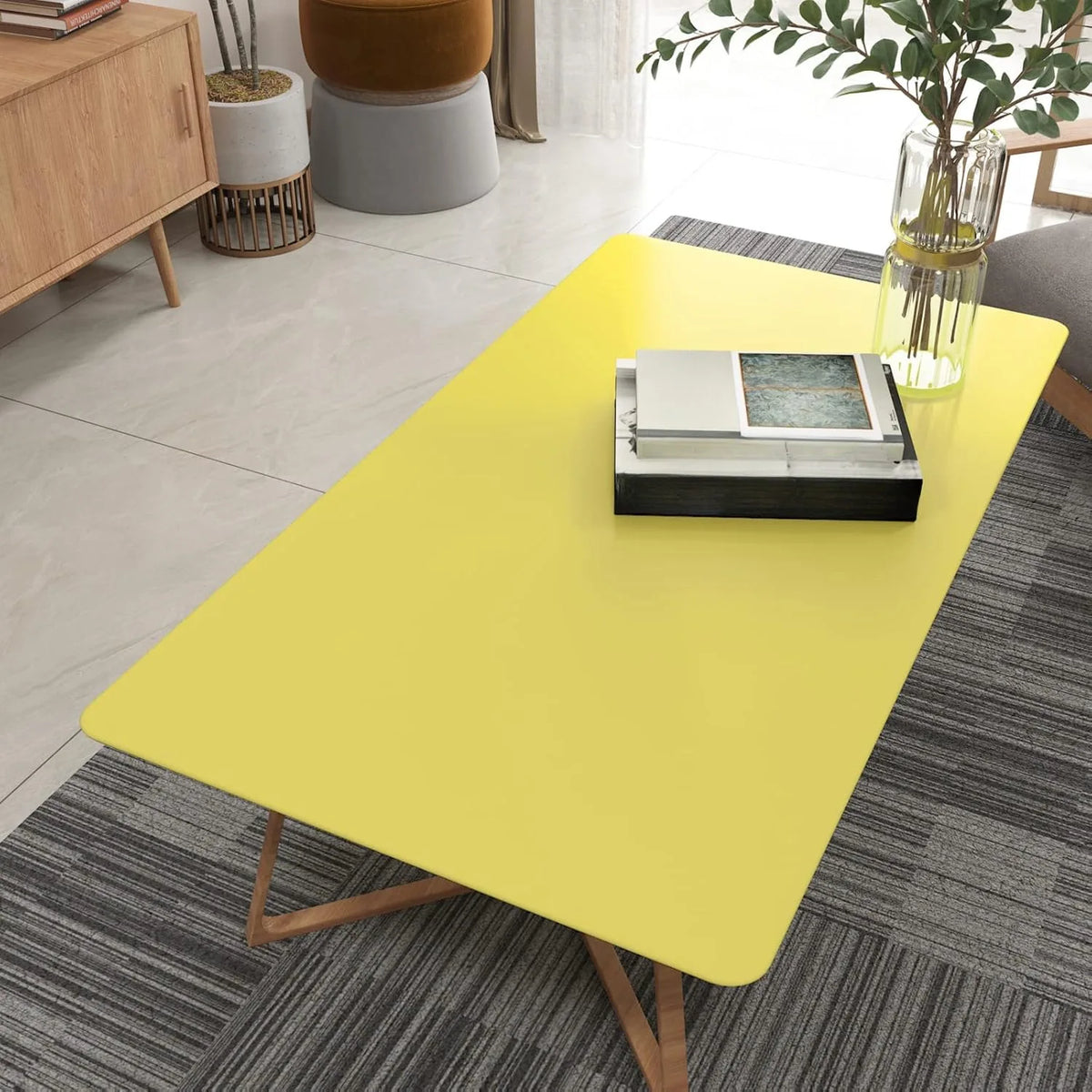 A bright yellow table with a black book on it is set in a modern living space.