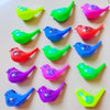 A collection of colorful plastic bird whistles in various shades including yellow, green, pink, and blue.