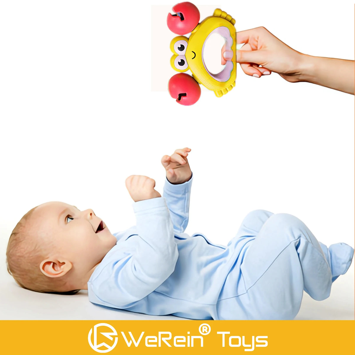 A baby is holding a yellow animal-themed rattle toy with red fruit pieces.