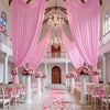 Pink drapierte Stoffvorhänge rahmen ein prächtiges Interieur mit Kronleuchtern und einer Holztür ein, verstreut mit rosa Blüt