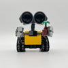Un mini robot amarillo y negro hecho de bloques de construcción con grandes ojos negros y acentos verdes.