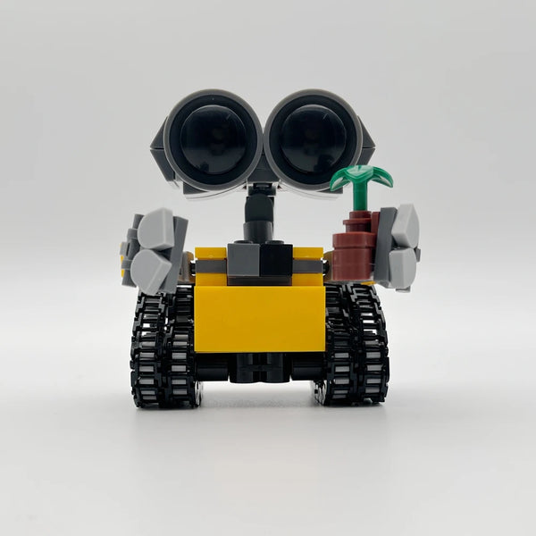 Mini robot jaune et noir construit avec des blocs de construction, grands yeux noirs et accents verts.