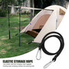 A beige tent is set up on a grassy field with an elastic storage rope lying in the foreground.