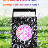 A black handheld bubble machine is shown surrounded by many iridescent soap bubbles on green grass.
