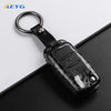 A black carbon fiber car key cover with a metal keyring and electronic features for VW and Skoda models
