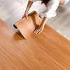 A person is applying self-adhesive wood grain wallpaper to a wooden surface.