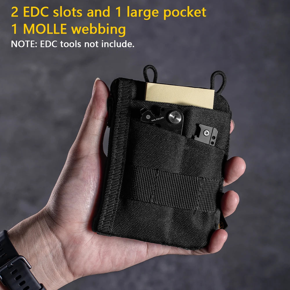 Una mano sostiene una bolsa organizadora EDC negra con dos compartimentos, un bolsillo grande y cinta MOLLE.