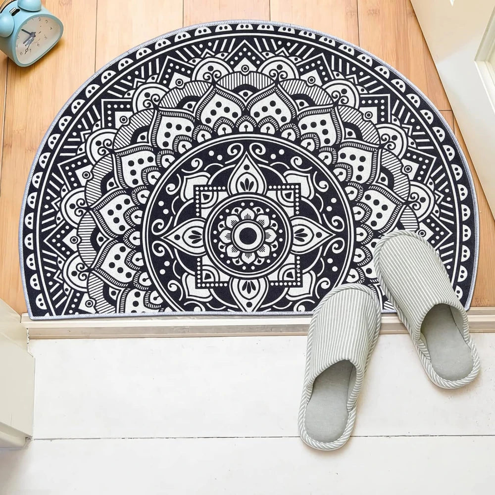A black and white tribal boho semi-circle doormat is displayed next to a pair of light gray woven slippers.