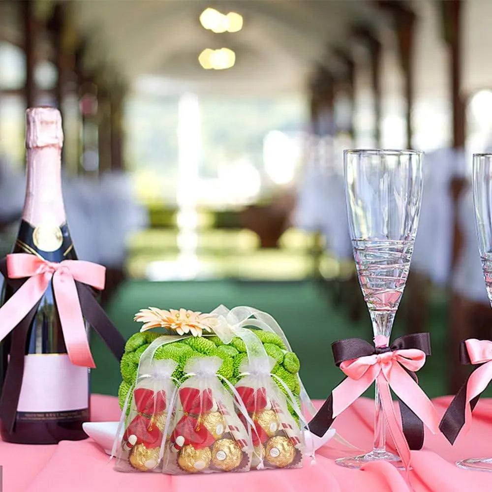 White organza drawstring bags filled with gold-wrapped items displayed on a pink table.