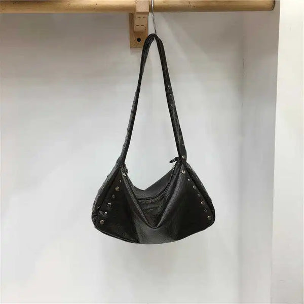 Schwarze Punk-Nieten-Rucksacktasche an einem Holzregal.