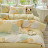 A bed dressed with a yellow and white patterned duvet cover set featuring geometric shapes and round accents.