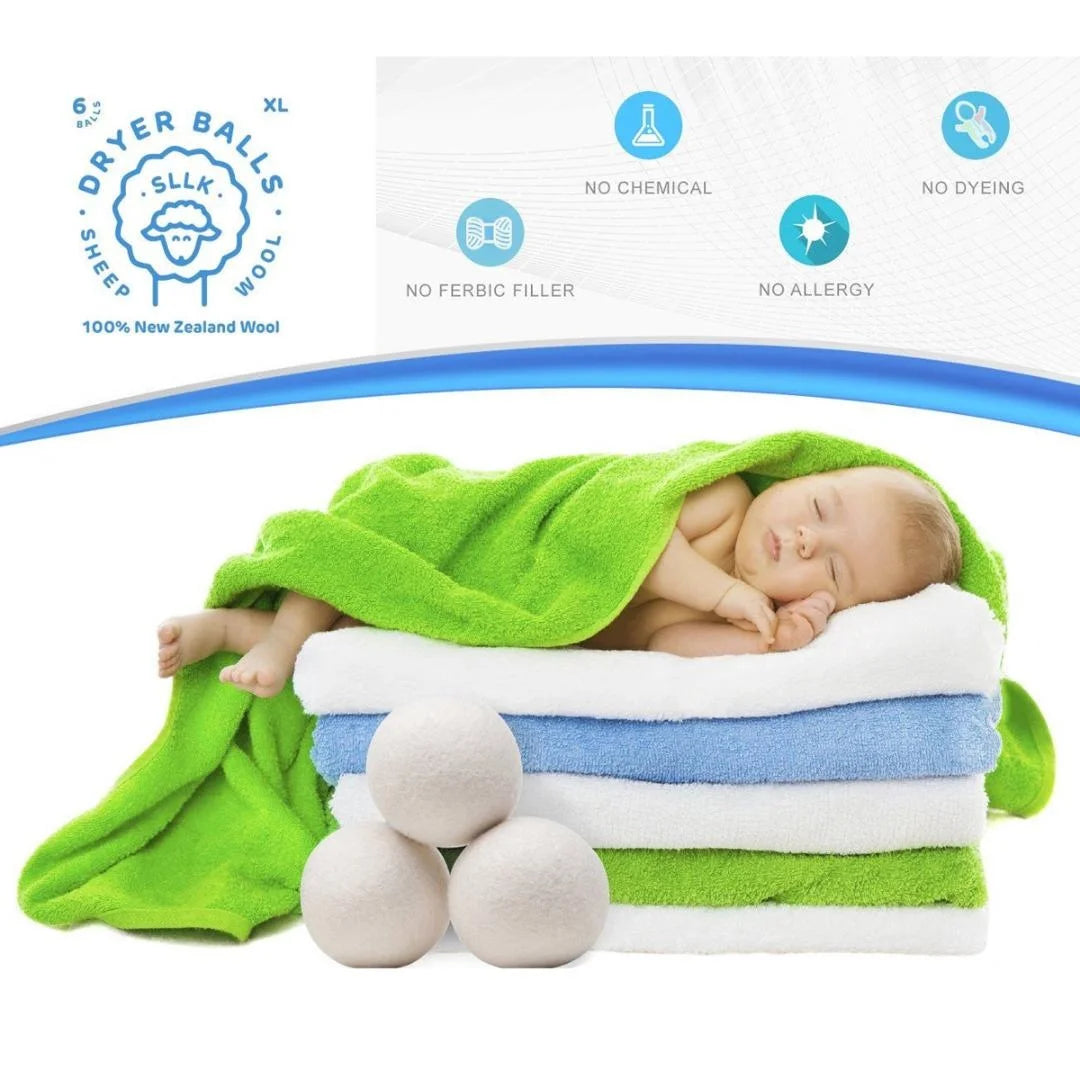 A newborn baby is sleeping on a white towel surrounded by natural wool dryer balls and green fabric.