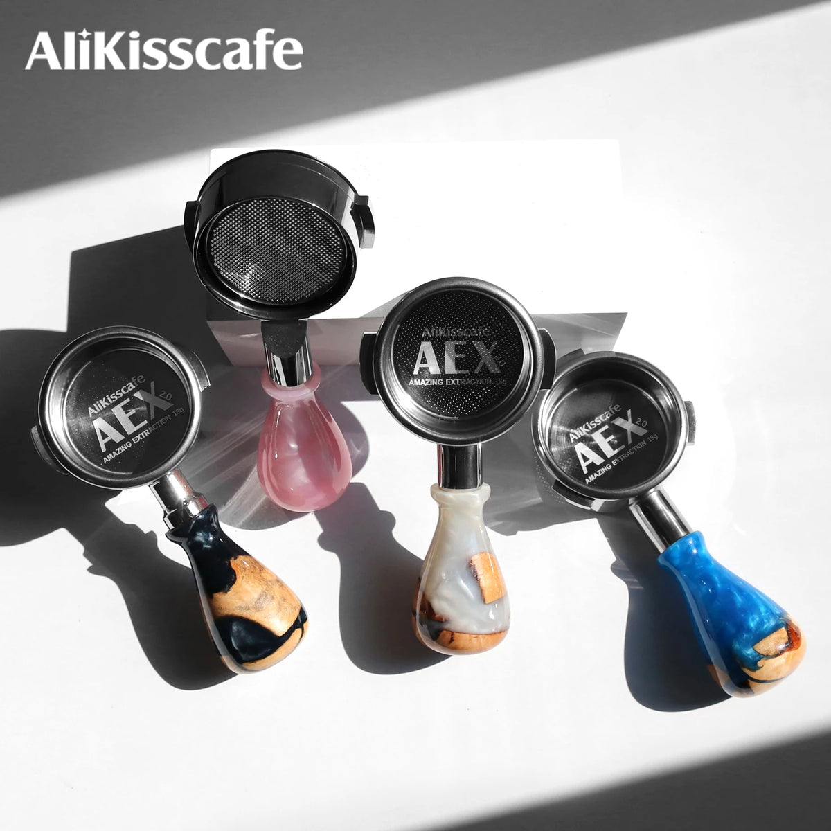 Three stainless steel bottomless espresso portafilters with colored handles displayed on a white background.