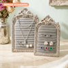 Silver arched resin jewelry display stand with floral design featuring various necklaces and earrings.