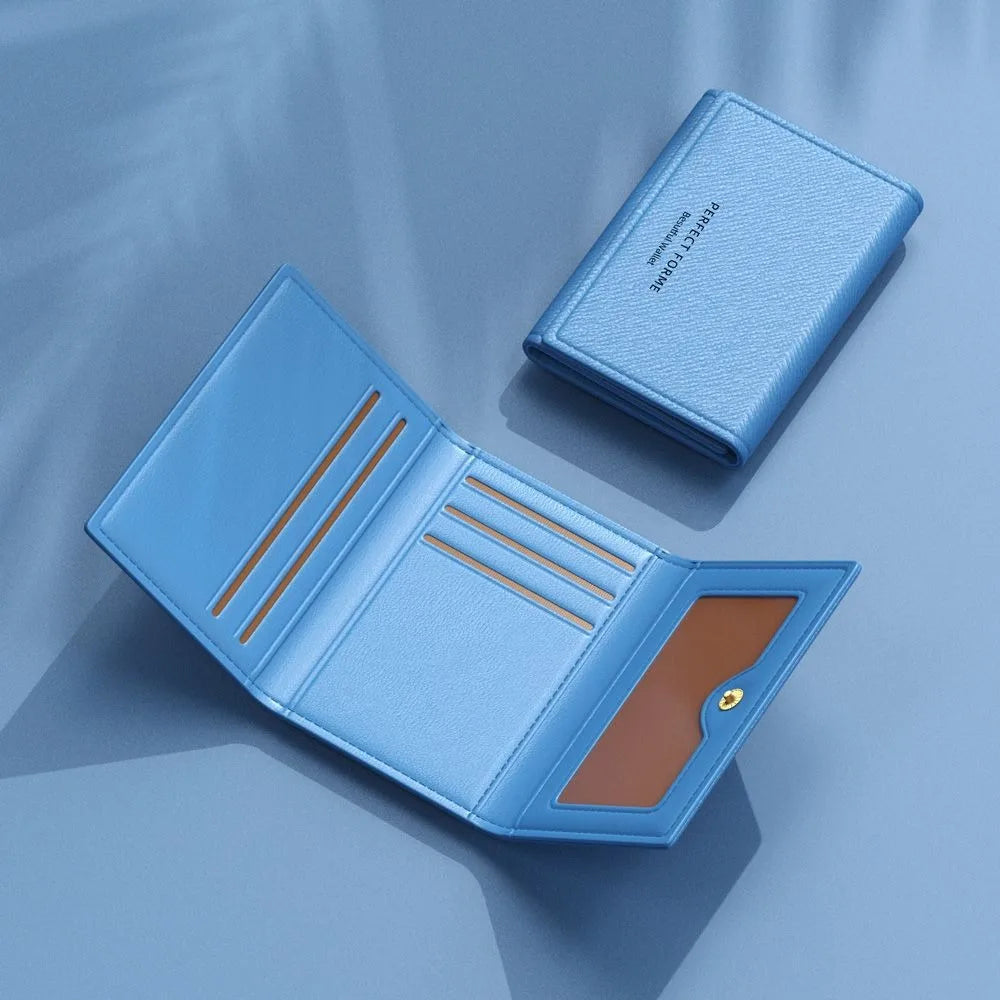 A light blue leather card holder wallet with multiple slots is shown open on a soft blue surface.