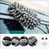 A close-up of a gray microfiber duster with a fluffy head being used to clean the exterior of a car window.