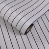 Roll of 3D grille pattern peel-and-stick wallpaper showing vertical black lines on a light gray background