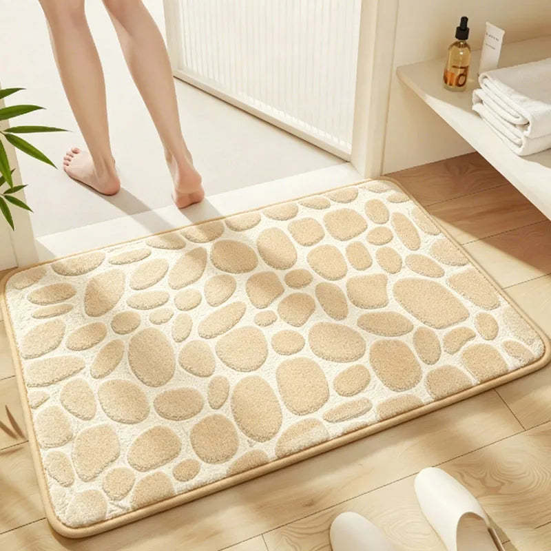 A beige plush non-slip absorbent bathroom rug with a pebble texture placed on a wooden floor.