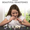 A girl is excavating colorful gemstones from a rock in a clear container.