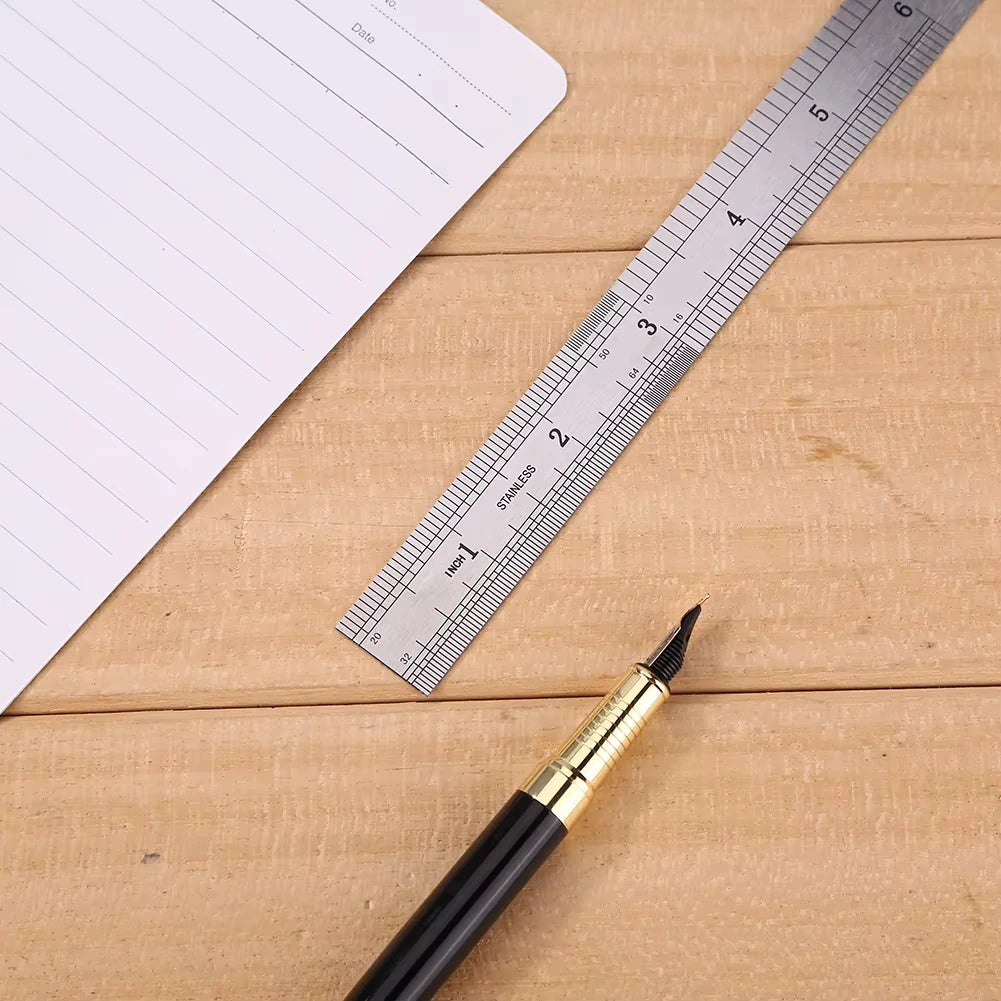 A black pen rests on a wooden surface next to a stainless steel precision ruler and a sheet of paper.