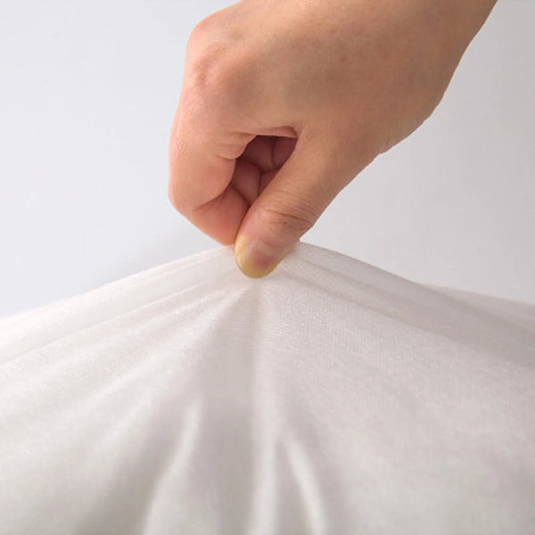 A hand is gently pressing down on a white fabric cushion to demonstrate its softness and texture.