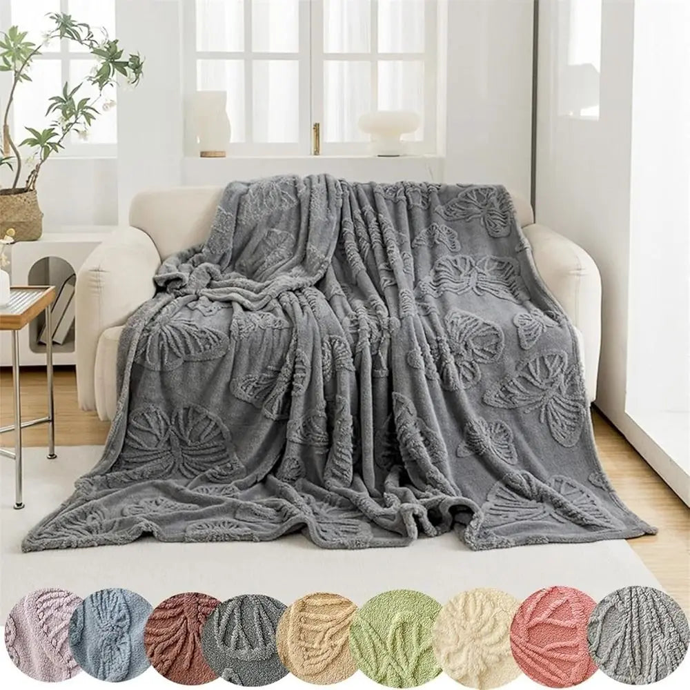 A gray double-sided cooling blanket draped over a white sofa in a bright room.